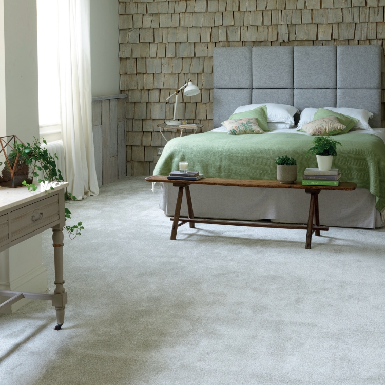 Neutral carpet, laid in a bedroom with wood cladded walls and coffee table at foot of bed.