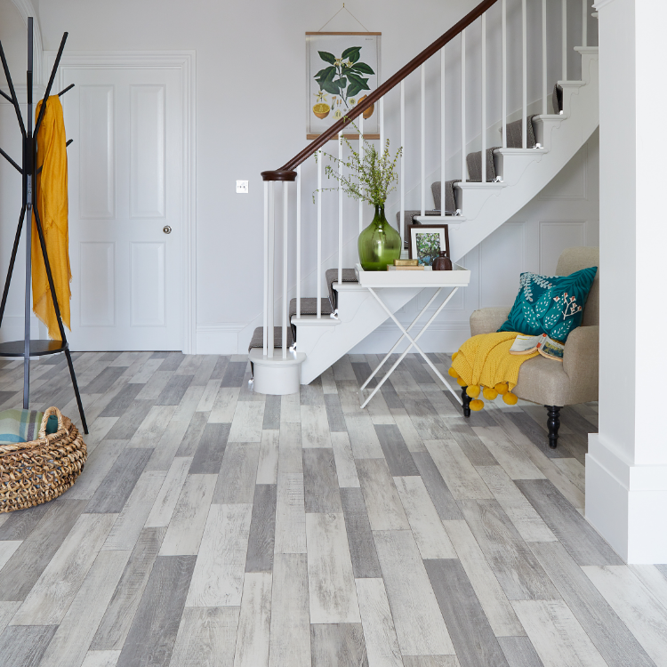 A hallway with yellow accessories and white stairs is shown with grey wood effect vinyl flooring