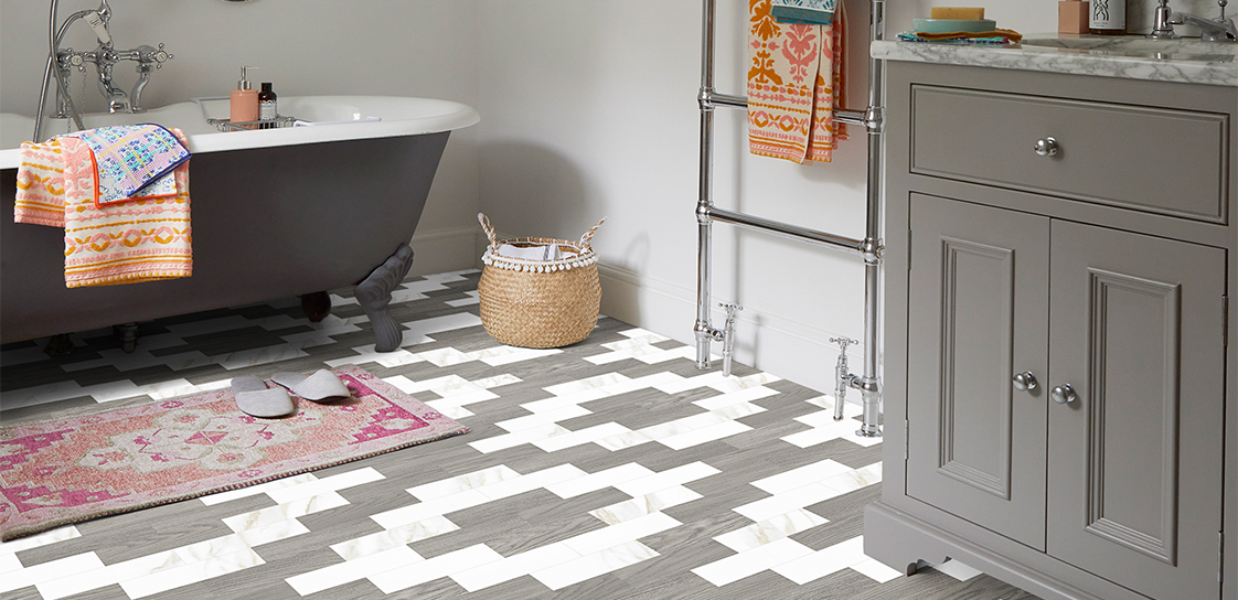 A patterned grey and white LVT floors in a grey bathroom with pink and orange accents
