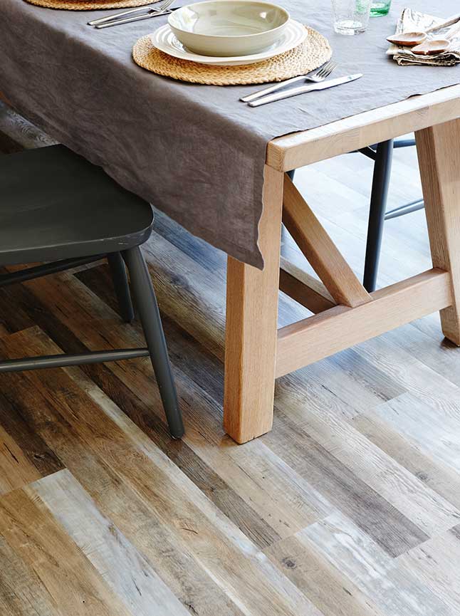 The legs of a wooden dining table and chair are visible against a backdrop of painted wood flooring
