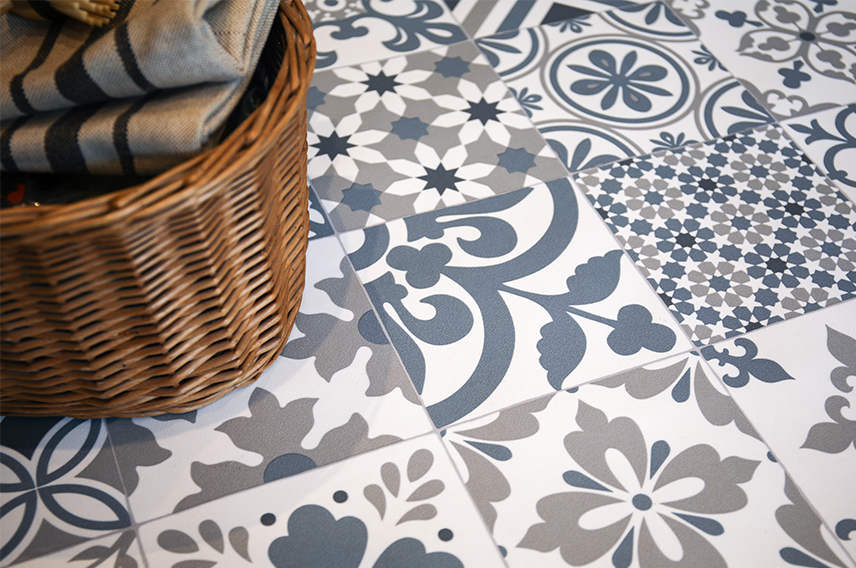 A close-up image of a laundry basket on a blue, white and grey tiled patterned vinyl