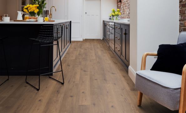 A large kitchen with island area, dark units and dark brown wood laminate floor