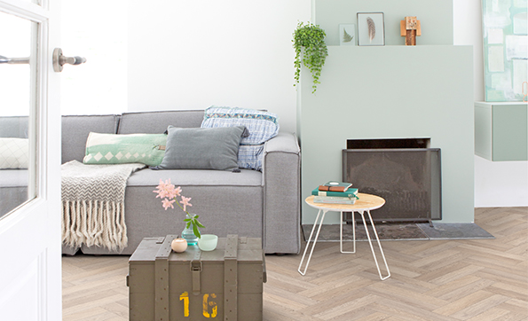 A living room with a light oak herringbone flooring, styled with a pastel coloured interior